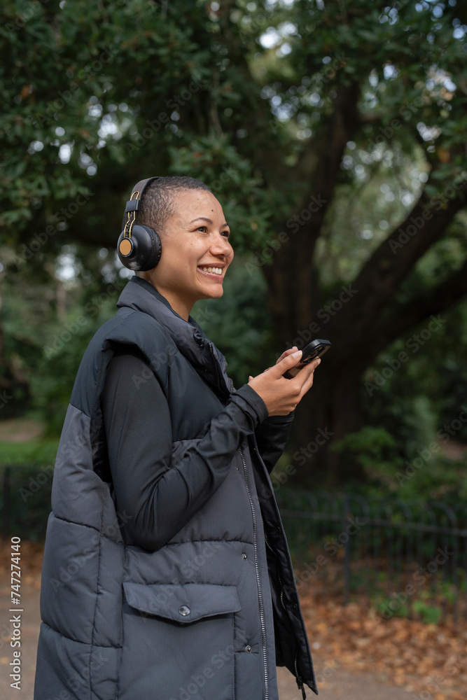Smiling woman with headphones and smart phone in park Smiling woman with headphones and smart phone in park