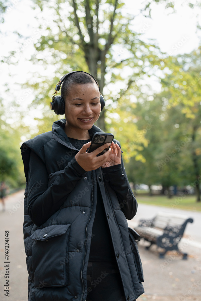Smiling woman with headphones and smart phone in park Smiling woman with headphones and smart phone in park
