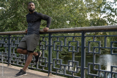 Athletic man leaning on footbridge in park