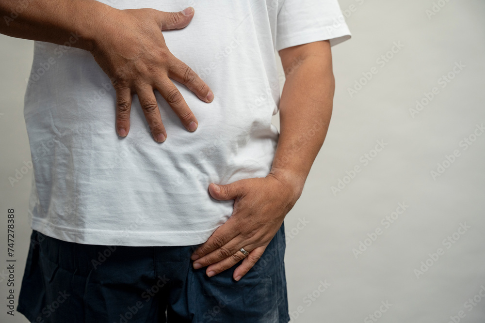 Man with hands on belly against gray background Man with hands on belly against gray background