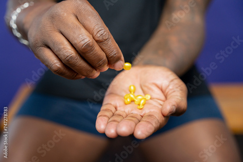 Close-up of man holding yellow capsules in hands