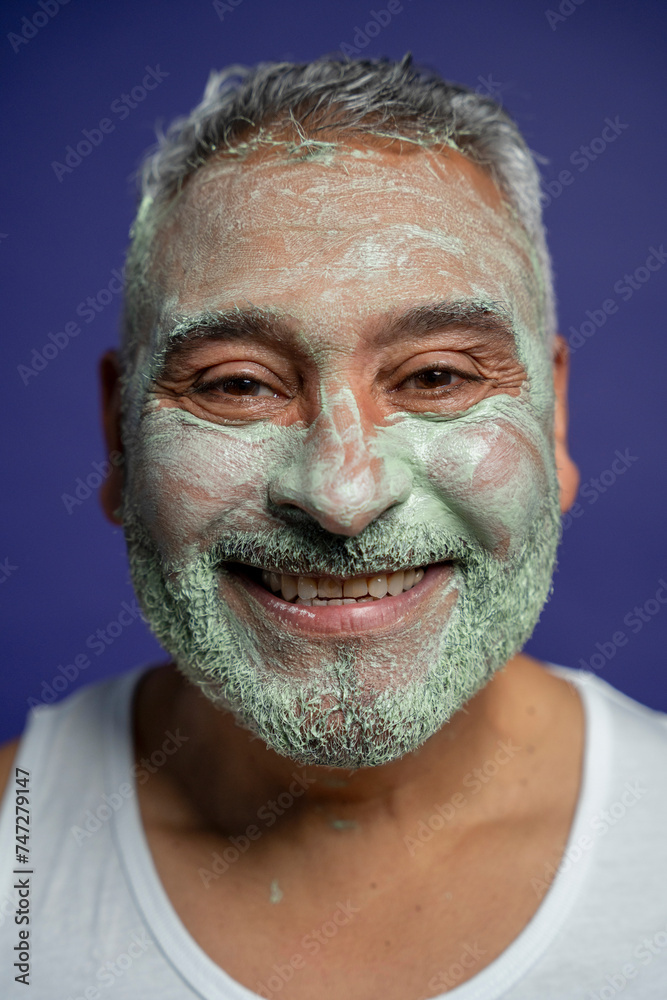 Portrait of smiling man with facial mask against purple background Portrait of smiling man with facial mask against purple background