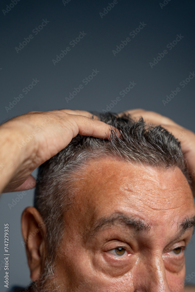 Fototapeta premium Close-up of man styling hair against gray background