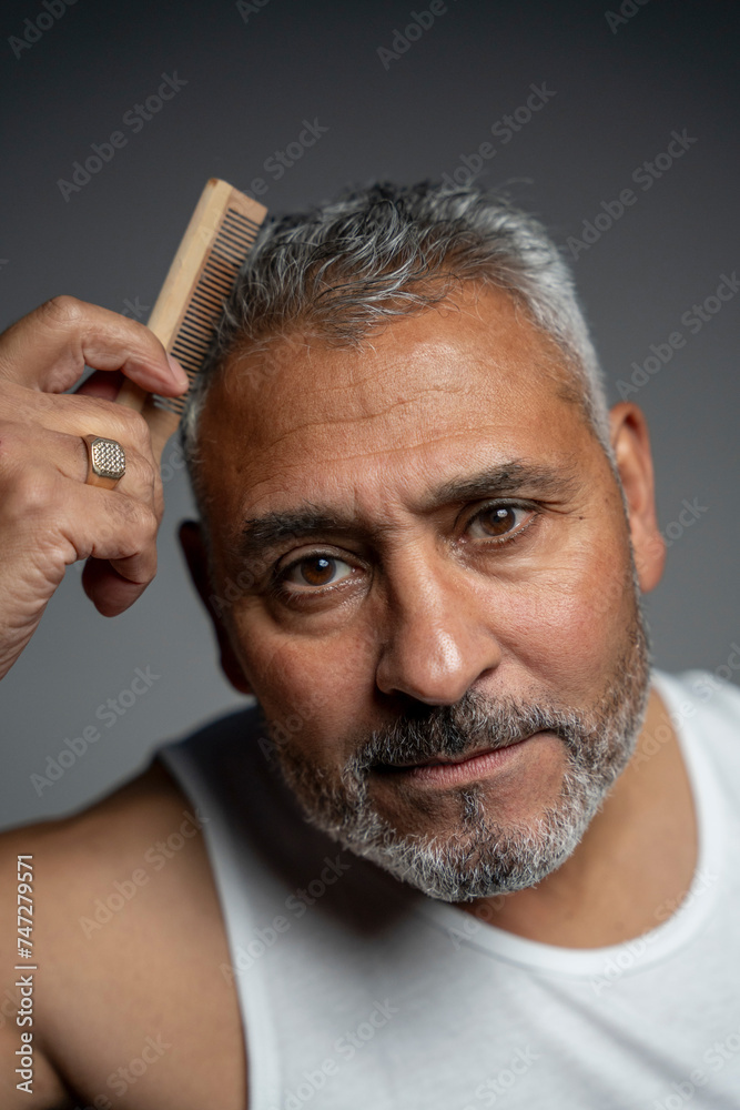 Obraz premium Portrait of man combing hair against gray background