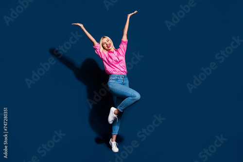 Full length photo of gorgeous woman wear stylish shirt holding arms up announcing sale empty space isolated on dark blue color background