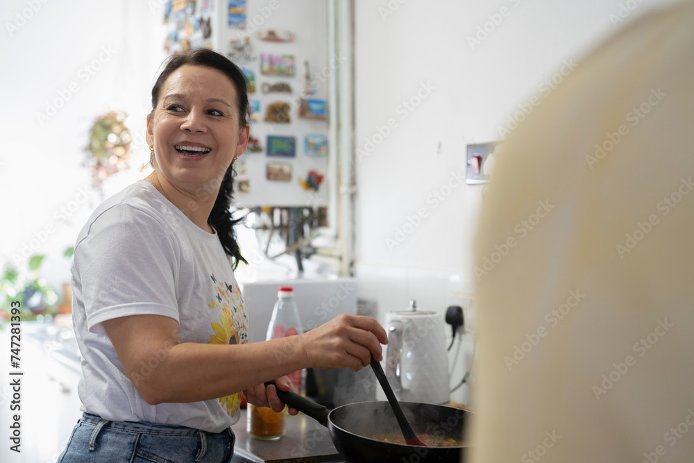 Mature woman preparing food in kitchen - obrazy, fototapety, plakaty 