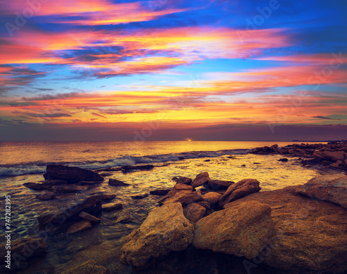 Seascape in the evening with a beautiful dramatic sunset sky. Wild rocky beach in the evening