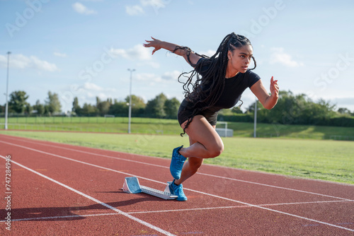 Female athlete sprinting off starting line at stadium