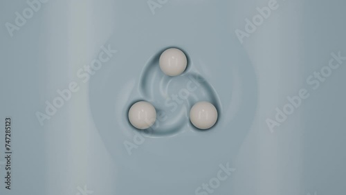 A looping 3D animation of a blue cream surface over which three white milk drops fly in a spiral, merging and separating. Drops leave a mark on the surface. Loop animation