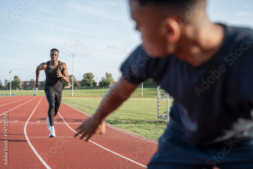 Photos Two athletes running in relay race