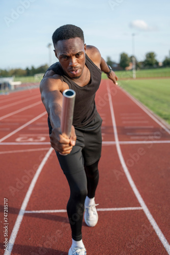 Athlete holding relay baton during race © Cultura Creative