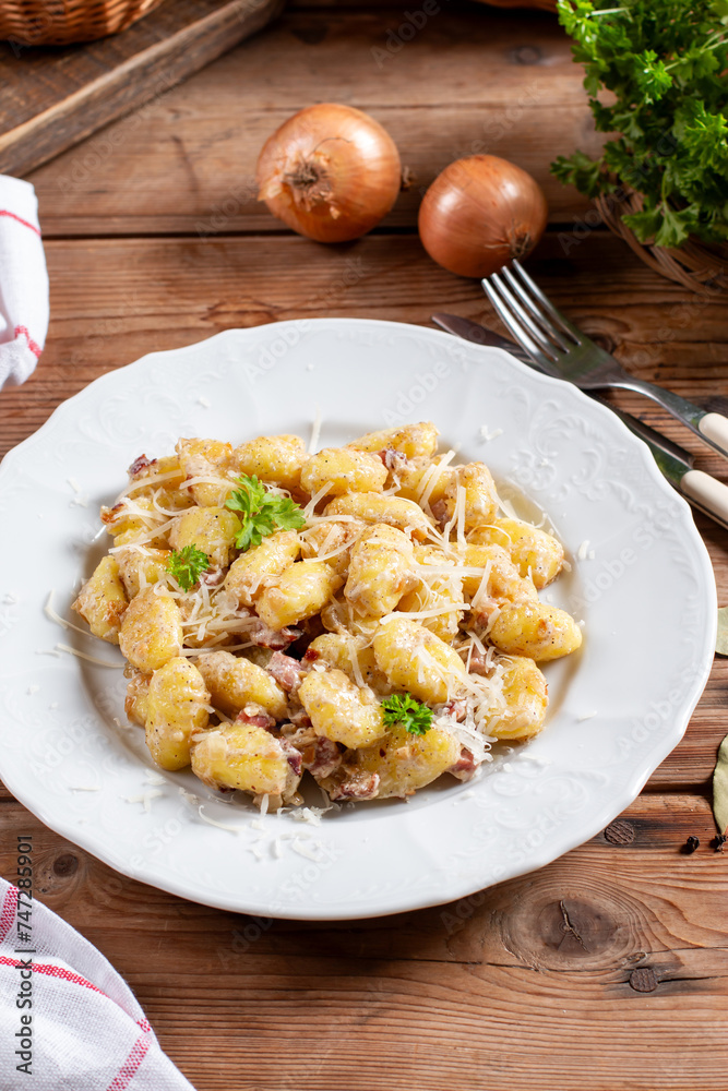 Plate of delicious gnocchi with creamy sauce on a wooden table Plate of delicious gnocchi with creamy sauce on a wooden table