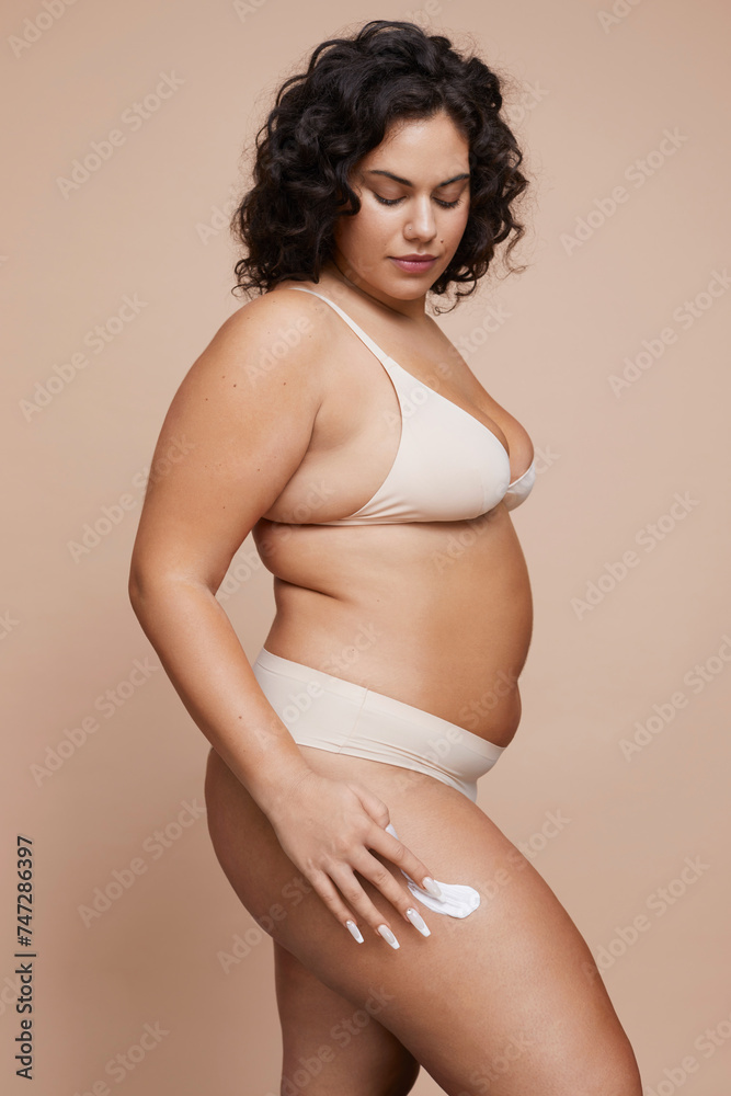 Studio shot of young woman using anti-cellulite cream Studio shot of young woman using anti-cellulite cream