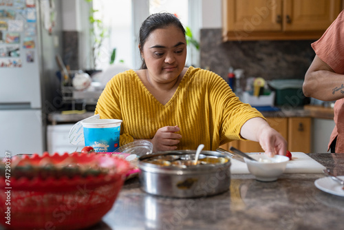 Young woman with down syndrome preparing food in kitchen