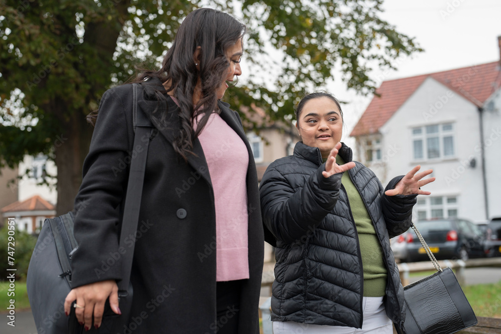 Mother walking with down syndrome daughter in residential district Mother walking with down syndrome daughter in residential district