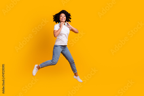 Full length photo of funky pretty lady dressed white t-shirt jumping enjoying music headphones empty space isolated yellow color background