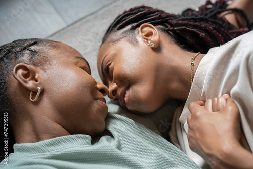 Portrait of smiling lesbian couple lying on floor at home