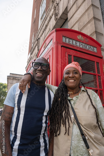 UK, London, Happy mature couple posing in front of traditional red telephone booth