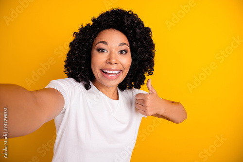 Photo of cheerful funky lady dressed white t-shirt showing thumb up recording video vlog isolated yellow color background