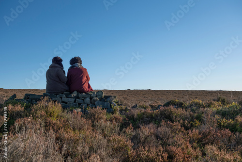 Rear view of two women sitting in moorland