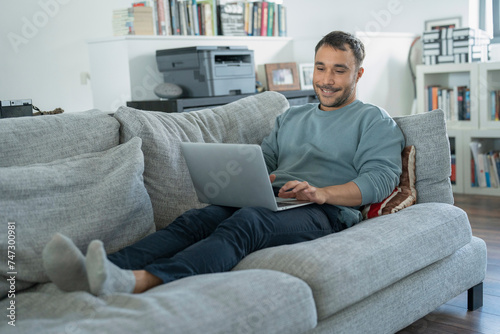 Smiling mature man working on laptop on sofa
