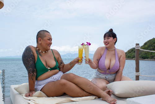 Cheerful women toasting with cocktails and relaxing near bay