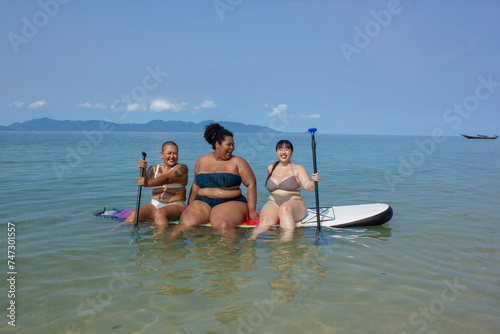 Group of cheerful women sitting on paddleboard