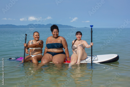 Group of cheerful women sitting on paddleboard