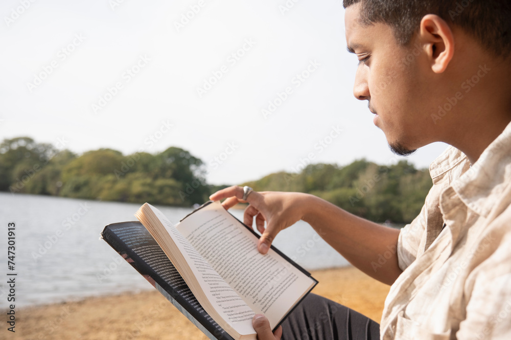 Close-up of man reading book on lakeshore