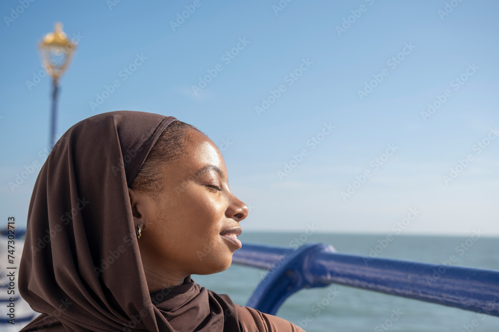 Portrait of Muslim woman with closed eyes by sea on sunny day Portrait of Muslim woman with closed eyes by sea on sunny day