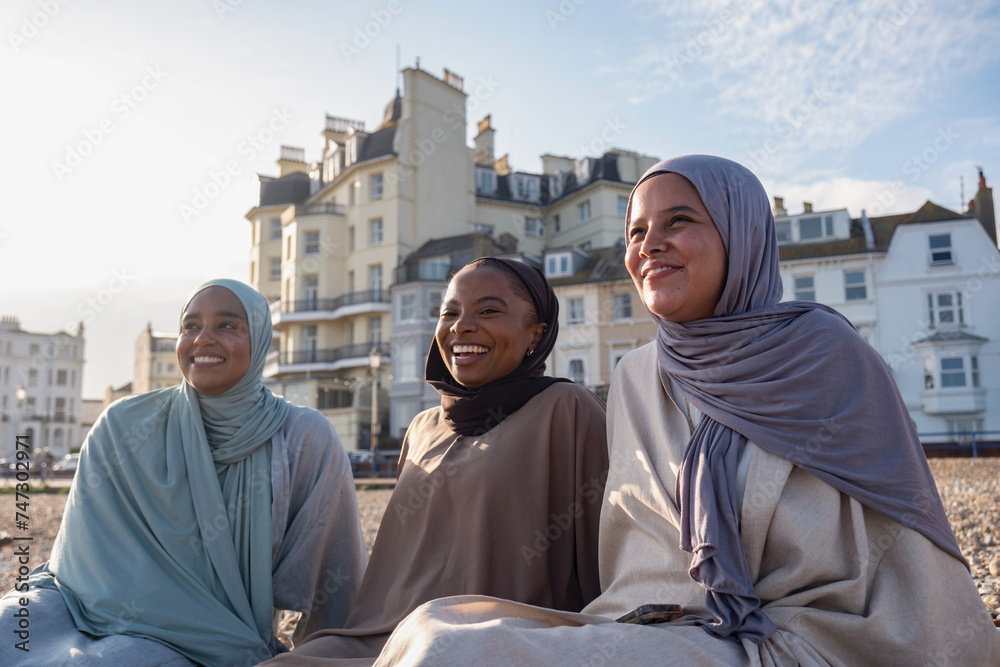 Three Muslim friends sitting on beach