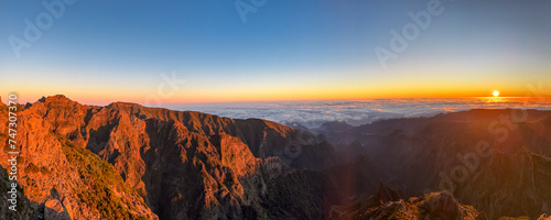 Panoramic view of majestic mountain ridges at sunrise seen from top of Pico do Areeiro, Madeira island, Portugal, Europe. First sunlight touching unique rock formations. Idyllic hiking trail at dawn photo