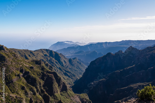 Scenic view of misty hills and cloud covered coastline of majestic Atlantic Ocean on Madeira island, Portugal, Europe. Idyllic hiking trail to mountain peak Pico Ruivo. Coastal landscape on sunny day