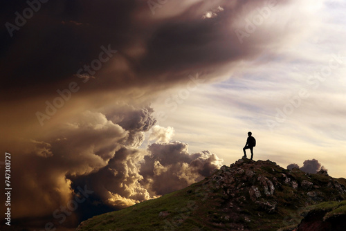 Ein Mann steht auf einem Berg und schaut in eine fantastische Wolkenlandschaft