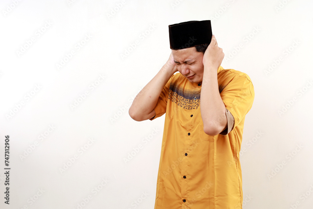 Stressed frustrated young asian muslim man covering his ears Stressed frustrated young asian muslim man covering his ears