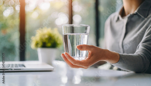 woman's hand trembling while holding a glass of water, depicting dystonia struggle photo