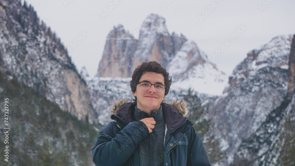 White man with glasses adjusting his jacket in the national park of Dolomites, in the Tre Cima di Lavaredo completely covered with snow on a winter day White man with glasses adjusting his jacket in the national park of Dolomites, in the Tre Cima di Lavaredo completely covered with snow on a winter day