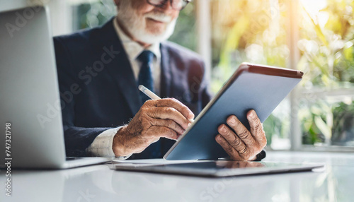 Senior Caucasian hands on iPad, tackling office tasks, symbolic of ageism and workplace bias photo