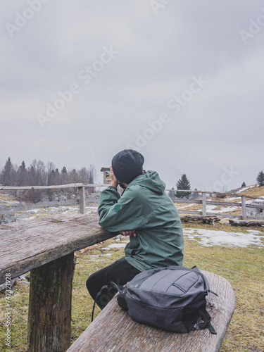 White man sitting on a bench in the mountains on a cloudy day. Watching the immensity of the mountains in the background of the Triglav National Park in Slovenia