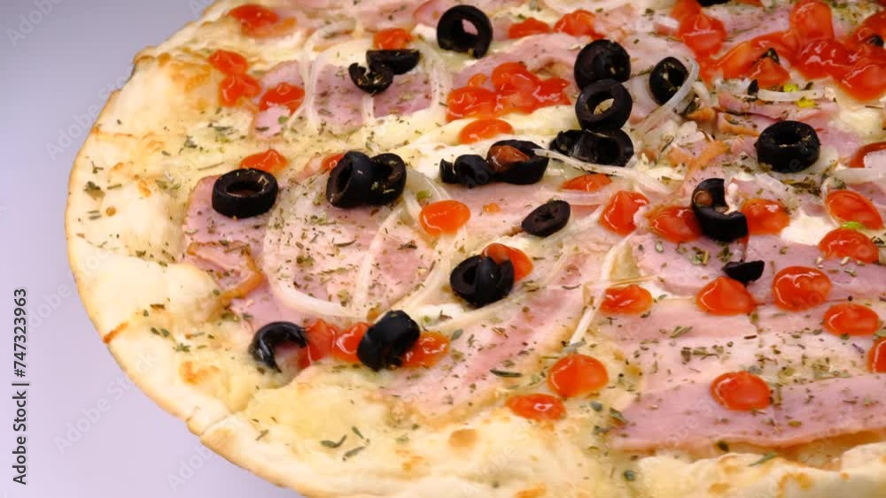 Pizza rotates on a white background, side view, close-up. Pizza with toppings, salami, tomatoes, fresh onions, ham, olives, peppers, cheese. Fast food. Pizza rotates on a white background, side view, close-up. Pizza with toppings, salami, tomatoes, fresh onions, ham, olives, peppers, cheese. Fast food.