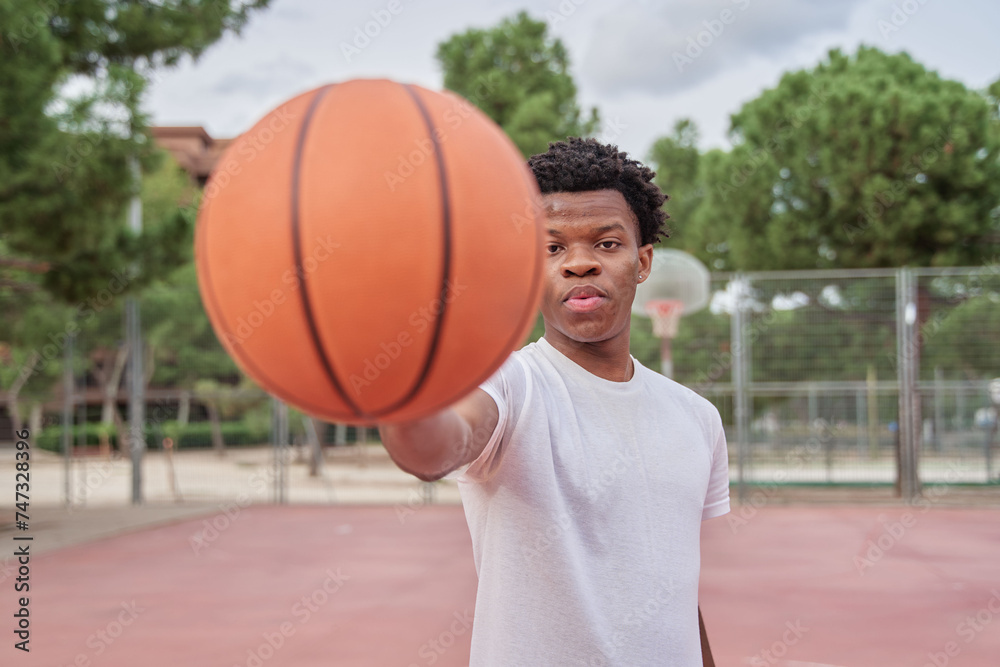 portrait of a young black man on a basketball court with a ball
