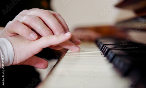 Experienced hand of the old music teacher helps the child student. Experienced master piano hand helps the student, close-up.