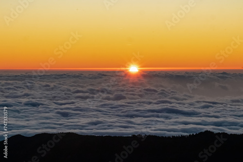 Panoramic view of sunrise seen from top Pico do Areeiro  Madeira island  Portugal  Europe. First sunlight touching surface of illuminated clouds covering the Atlantic Ocean. Dramatic red orange sky