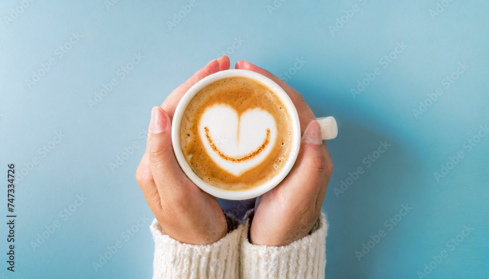Hands holding a cup of coffee with a happy face and heart emoji, blue background, copy space

 - obrazy, fototapety, plakaty 