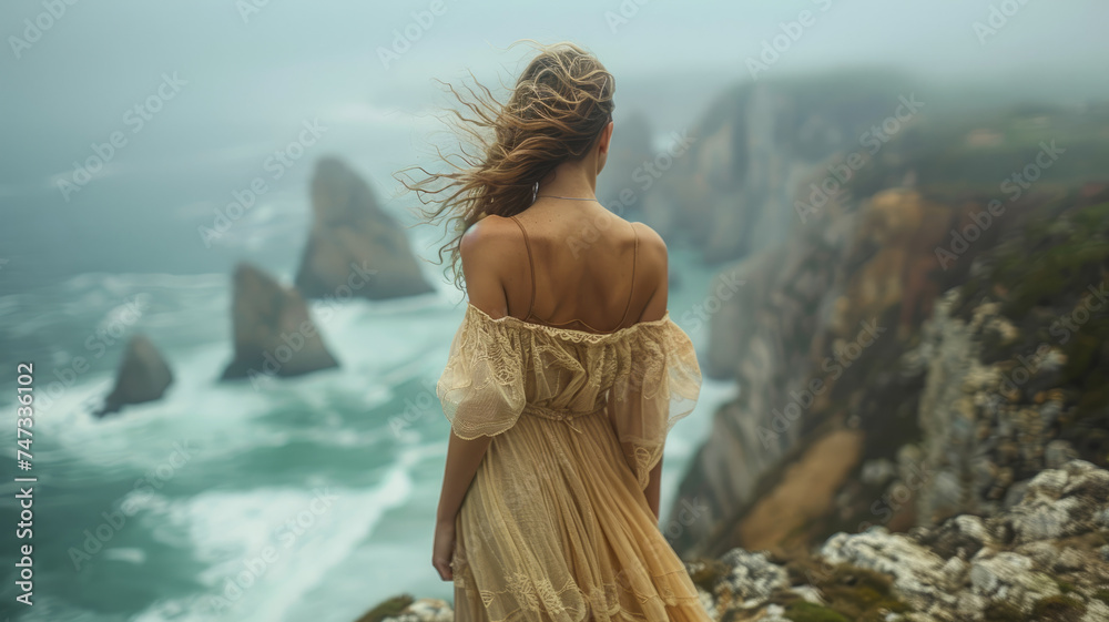 A lady in a beautiful dress enjoying the ocean view.