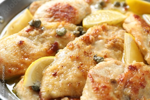 Delicious chicken piccata with lemons as background, closeup photo