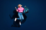 Full body photo of attractive young woman jump raise fists shopping dressed stylish pink clothes isolated on dark blue color background