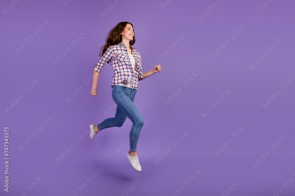 Portrait of sportive active girl in motion jumping over in the air isolated on violet color background Portrait of sportive active girl in motion jumping over in the air isolated on violet color background