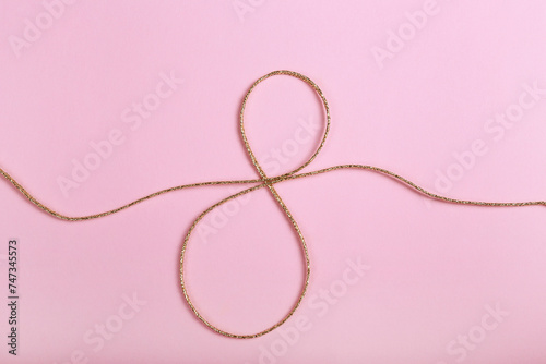 Golden jute twine in the shape of eight as symbol of symbol of women's equality. International women's day concept. Close up, copy space for text, background.