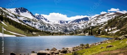 A mountain lake is nestled among snow-capped peaks atop Independence Pass. The tranquil water reflects the stunning snowy landscape  creating a picturesque scene of natural beauty.